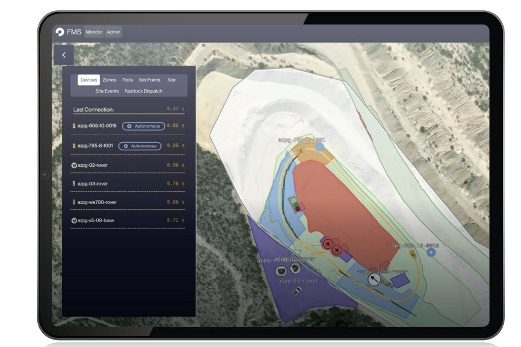 Tablet displaying a fleet management system map with autonomous vehicles and color-coded zones at a worksite.
