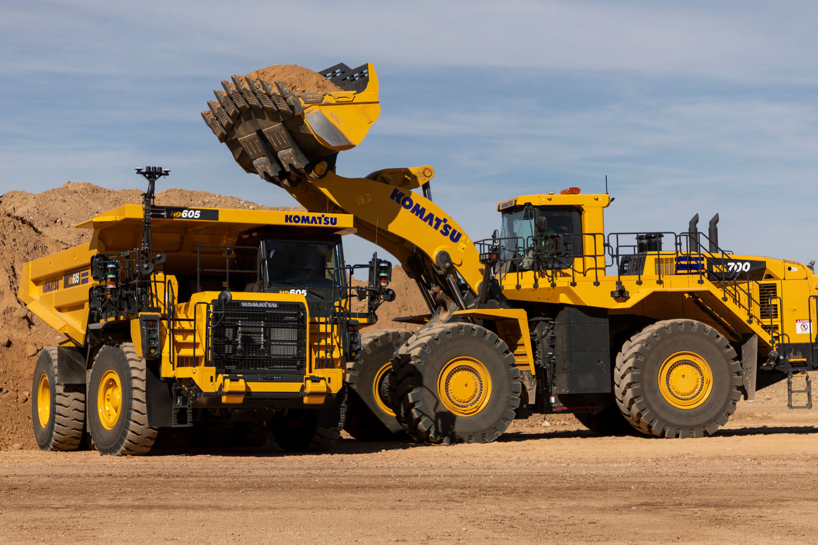Large yellow Komatsu truck parked beside a wheel loader.
