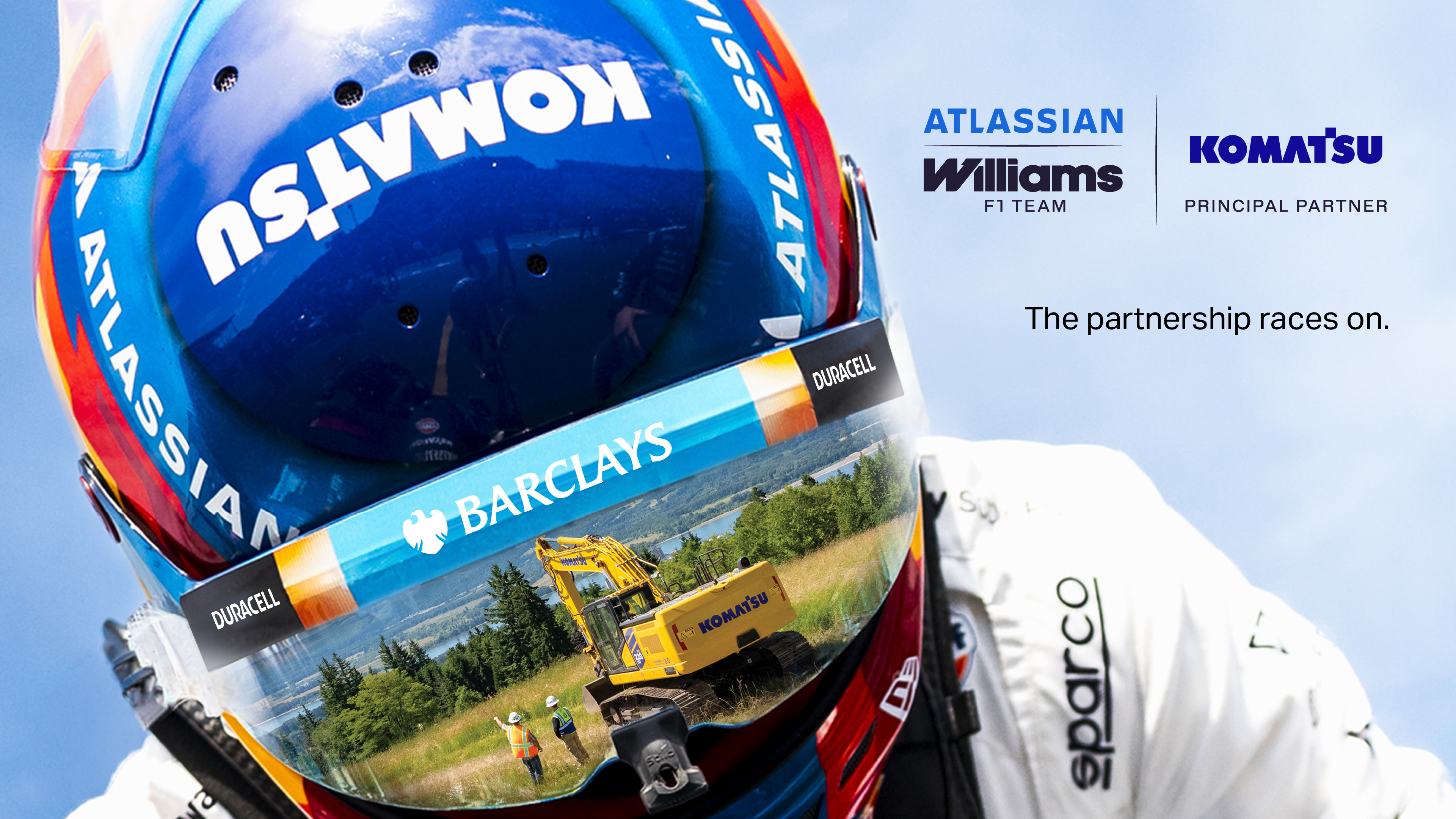 Close-up of a racing helmet featuring Komatsu branding and a reflection of a Komatsu excavator at a worksite. The image includes the Atlassian Williams Racing and Komatsu Principal Partner logos alongside the text, "The partnership races on."