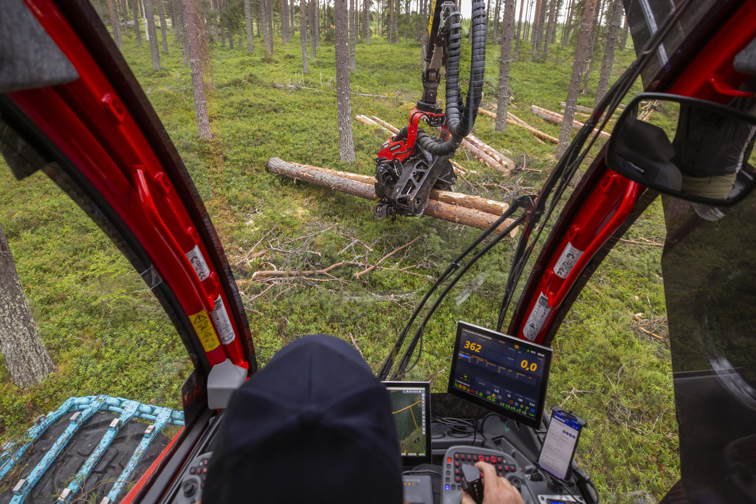 View from inside the cab of a forestry harvester operating in a forest.