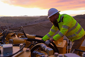 مهندس يشغّل معدات ثقيلة عند غروب الشمس