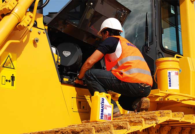 فنّي يؤدي أعمال الصيانة لمعدات الإنشاءات من Komatsu