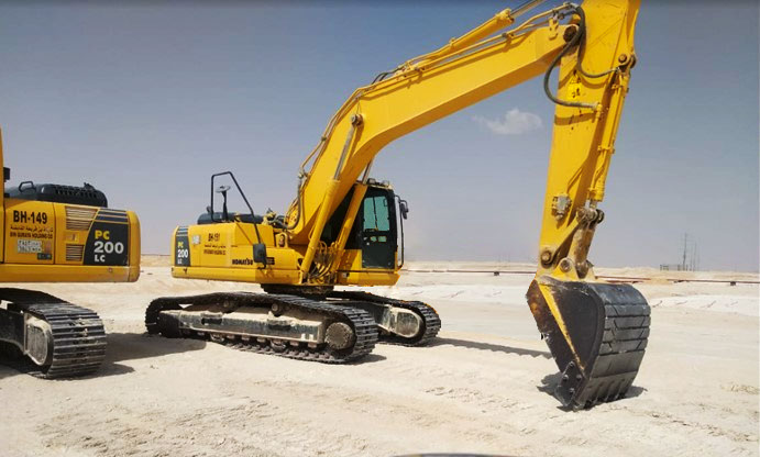 A yellow Komatsu PC 200 LC excavator from the Bin Quraya fleet, parked on a sandy construction job site.