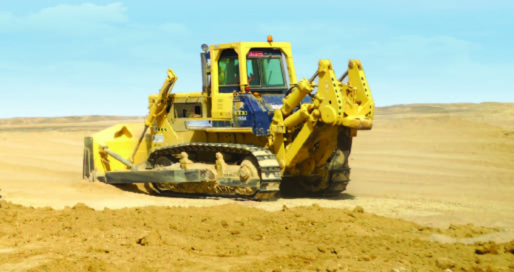 جرار أصفر كبير يعمل في موقع بناء جاف ومستوٍ