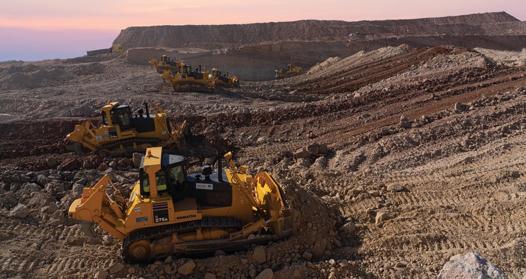 جرار أصفر كبير يعمل في موقع بناء جاف ومستوٍ