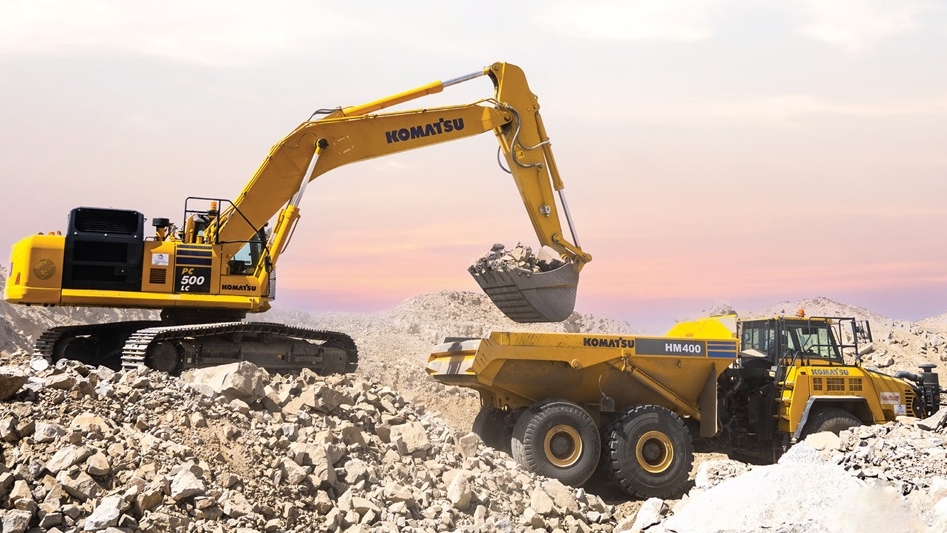 حفارة Komatsu تقوم بتحميل الصخور في شاحنة التفريغ Komatsu HM400 في موقع بناء وعِر عند الفجر أو الغسق