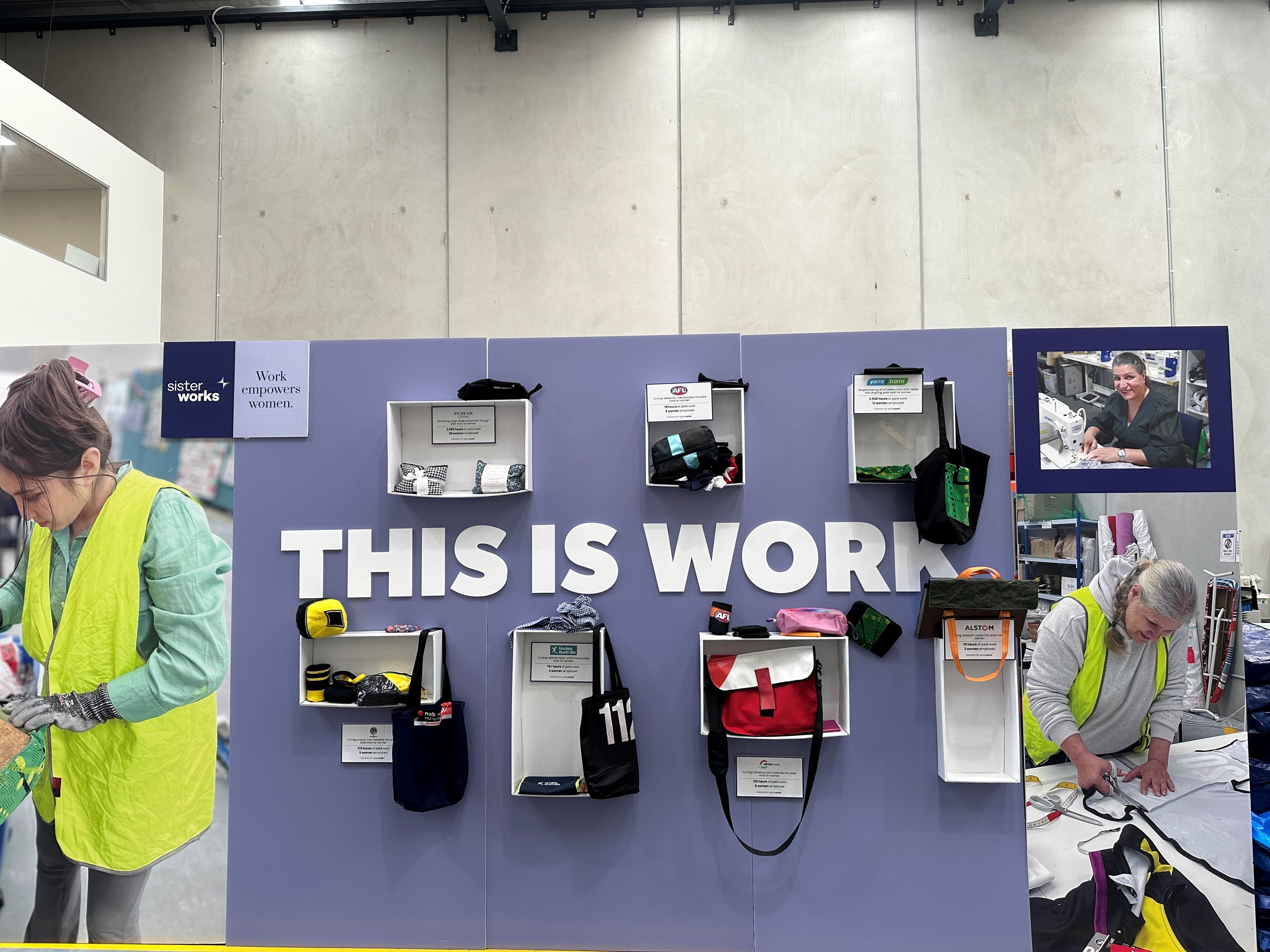 isplay wall with the message "THIS IS WORK" in large letters. Various bags and accessories are showcased in open boxes.