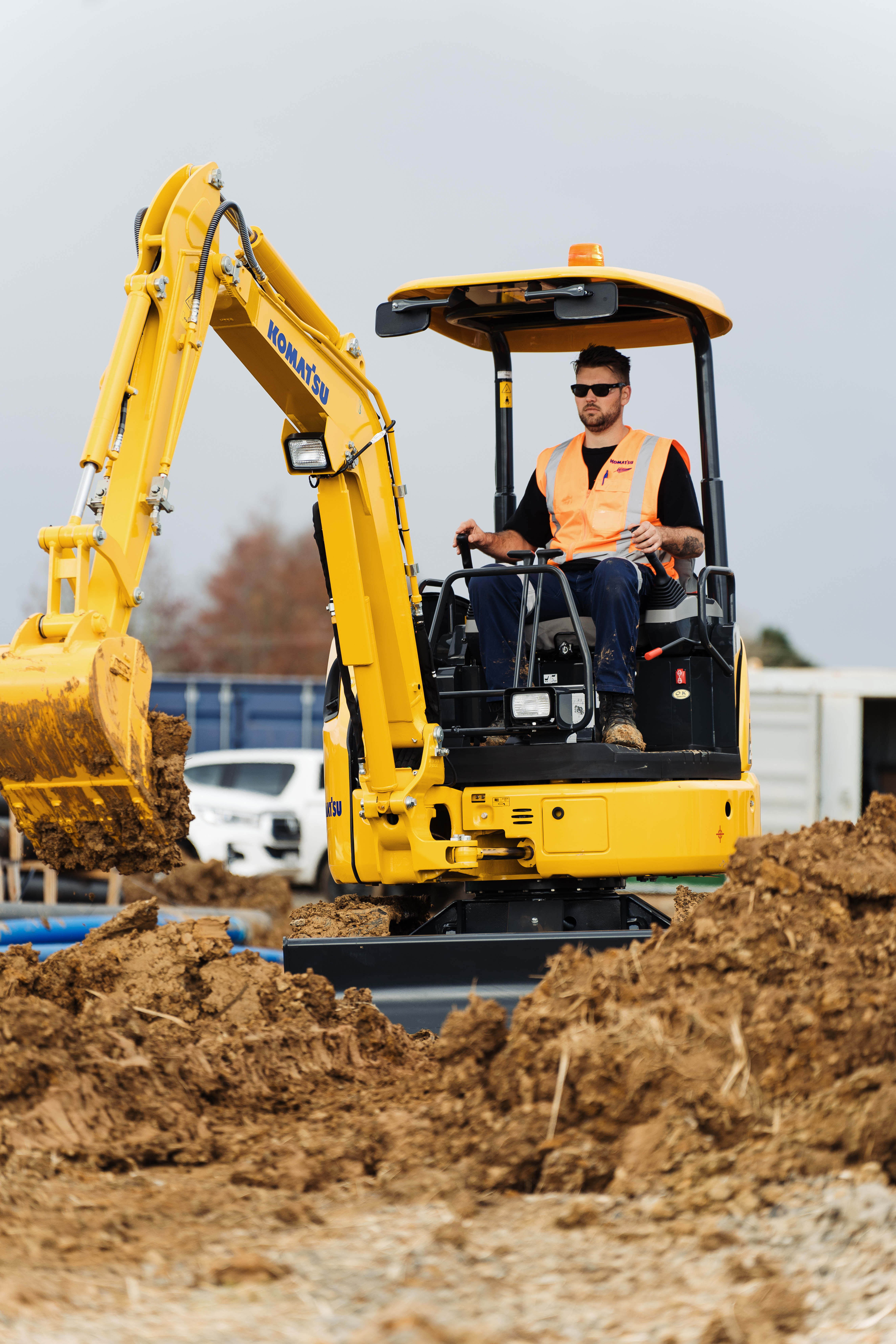 An man operating a Komatsu excavator on a construction site.