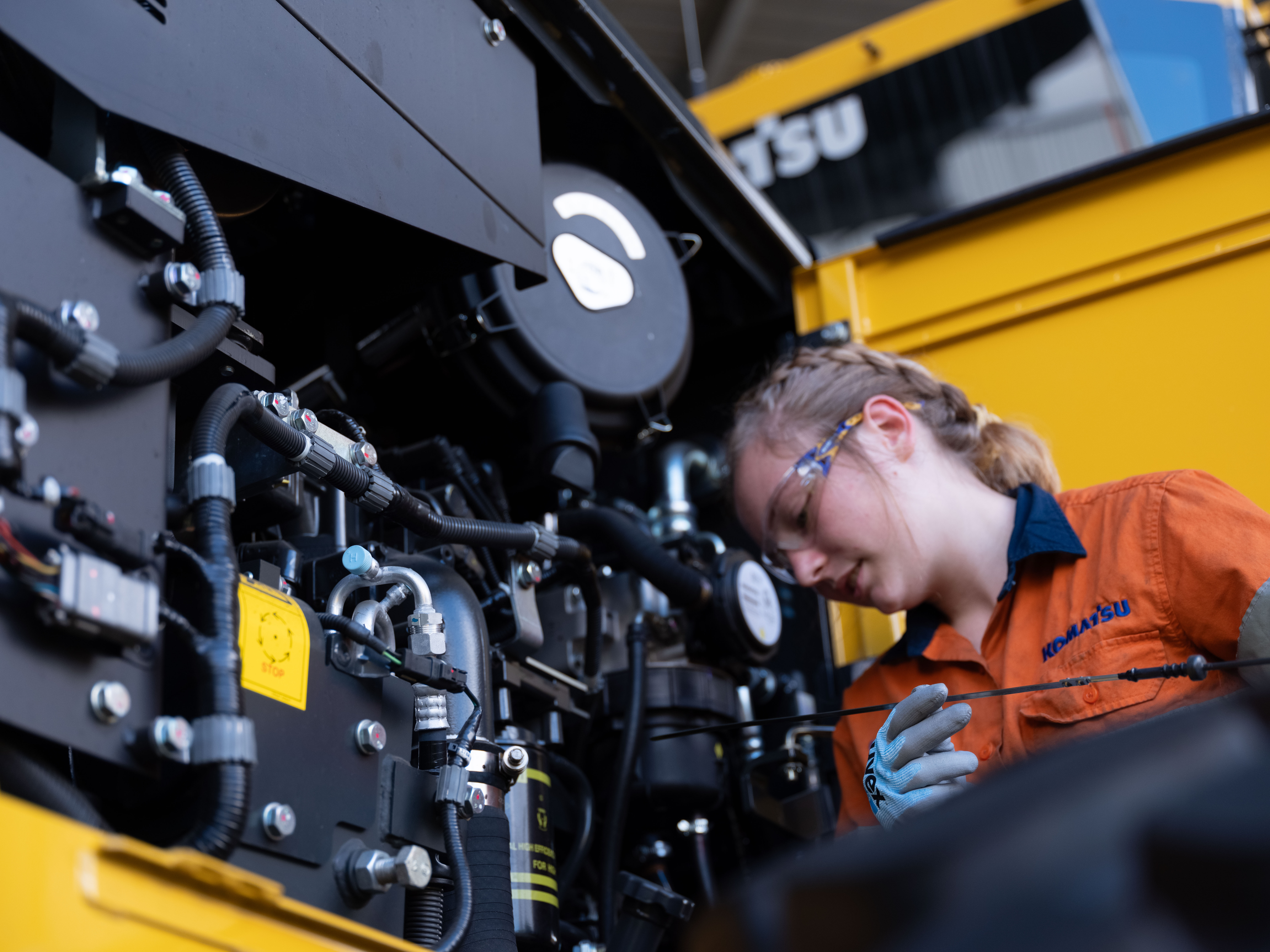 A Komatsu technician servicing a machine's engine component.