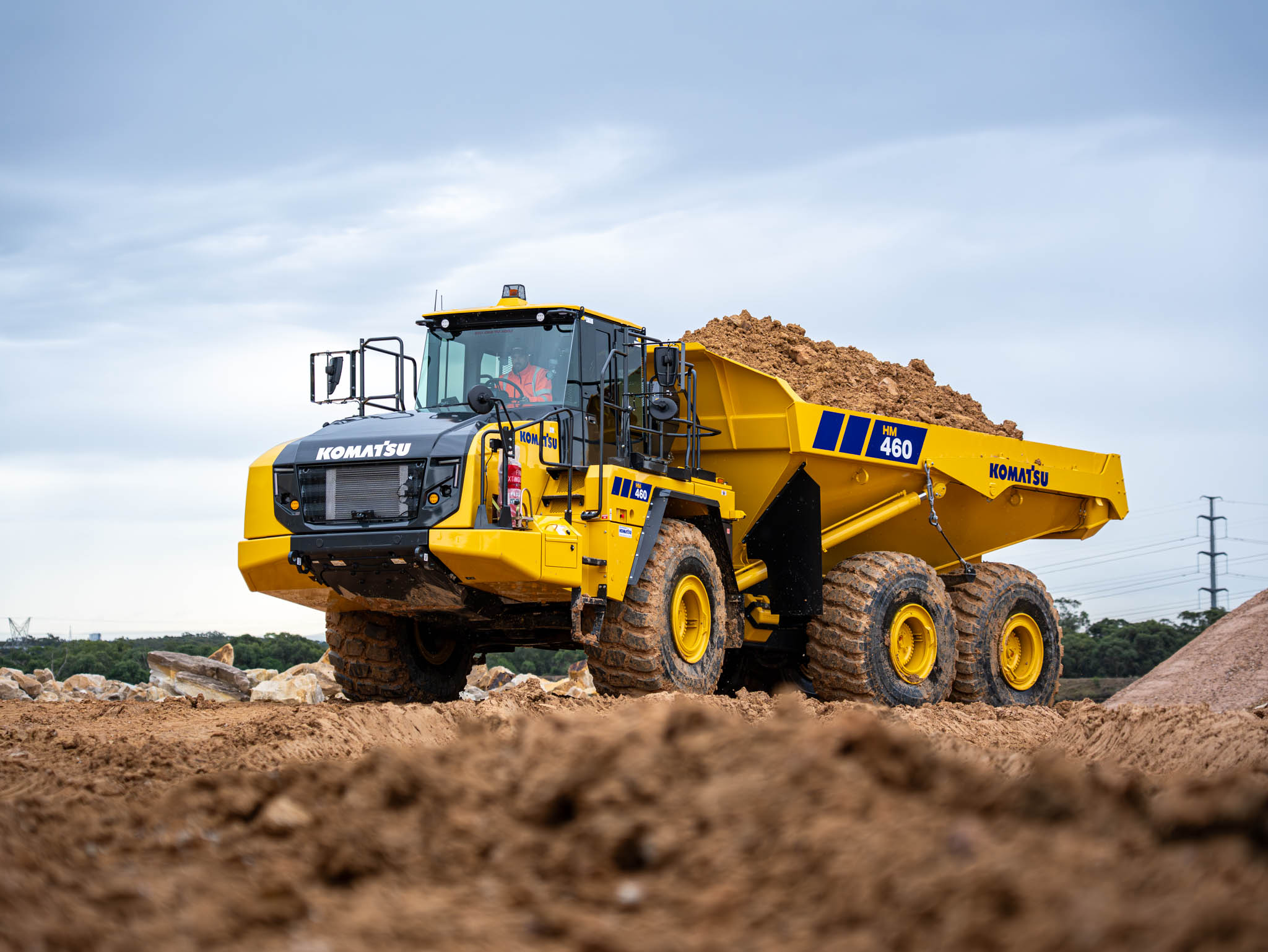 A Komatsu dump truck with a full load of dirt on a mine or quarry site.