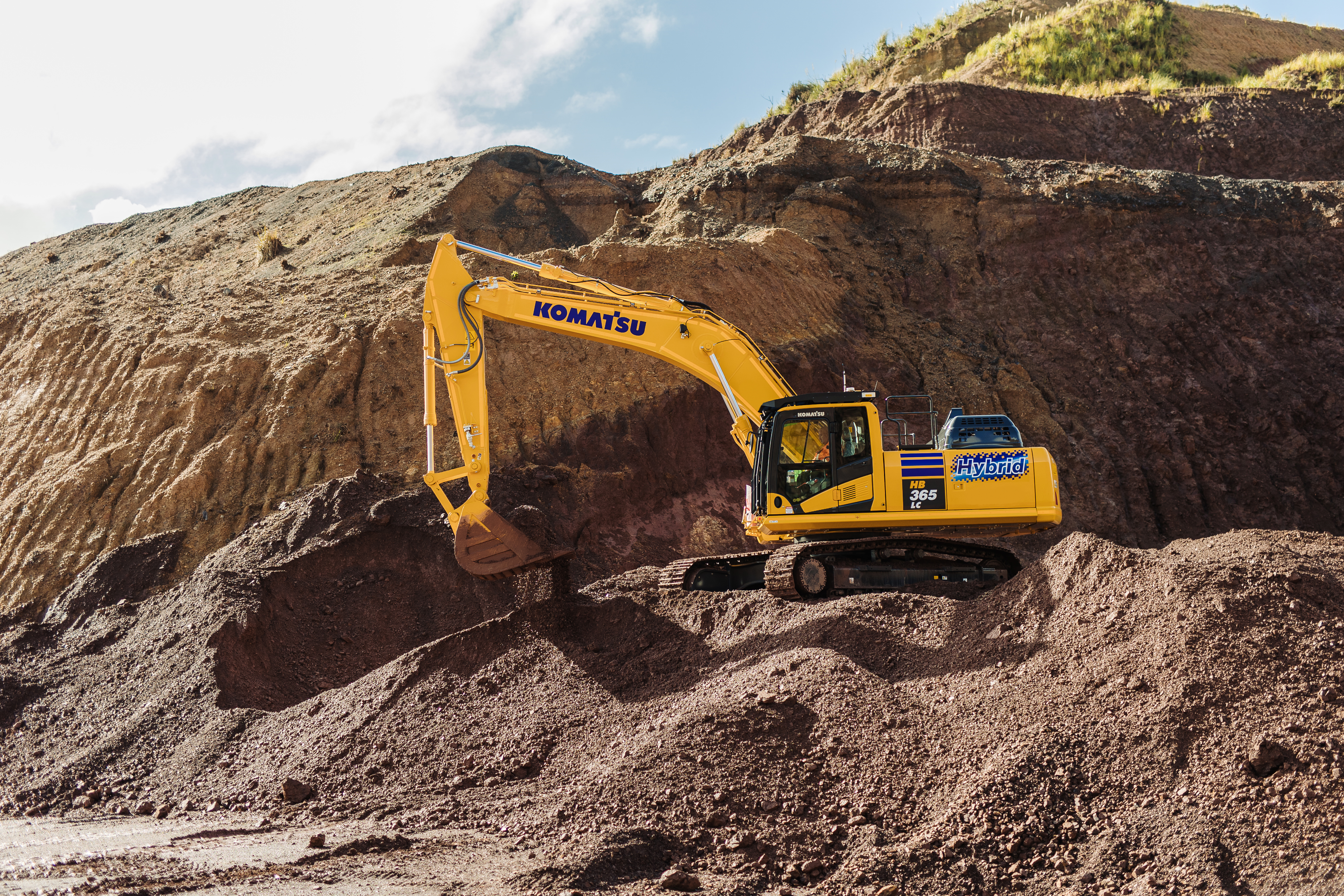 A Komatsu hybrid excavator on a mine or quarry site.