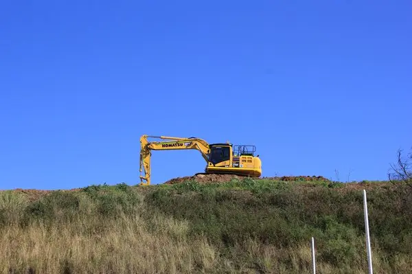 Komatsu excavator on a cliff with a blue sky as background