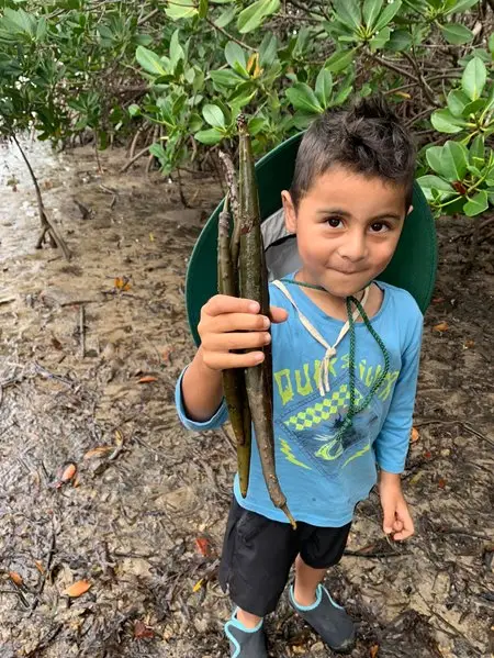 A kid with blue shirt holding up tree roots - JC Nyssens LYD 2022
