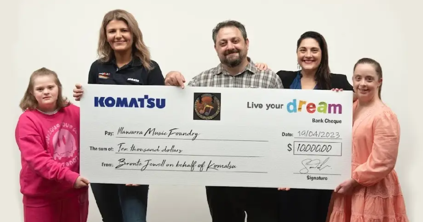 5 people standing with large Komatsu Live Your Dream cheque
