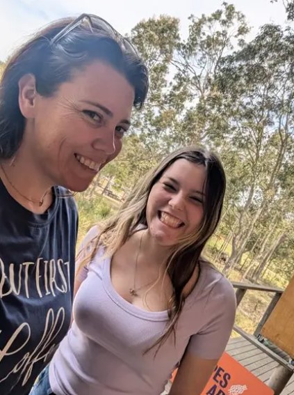 Two individuals smiling for the photo, in an outdoor setting with trees in the background.