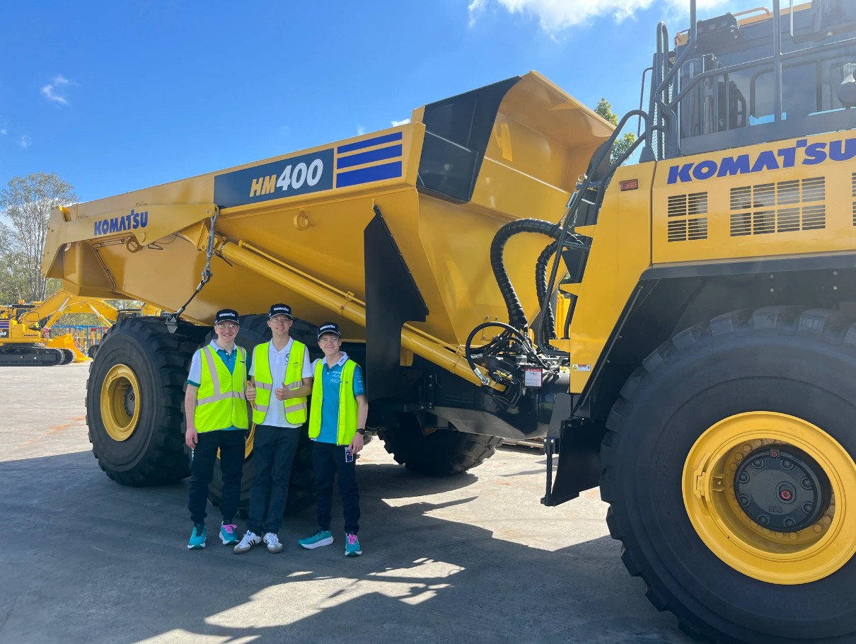 people posing in front of a large Komatsu machine