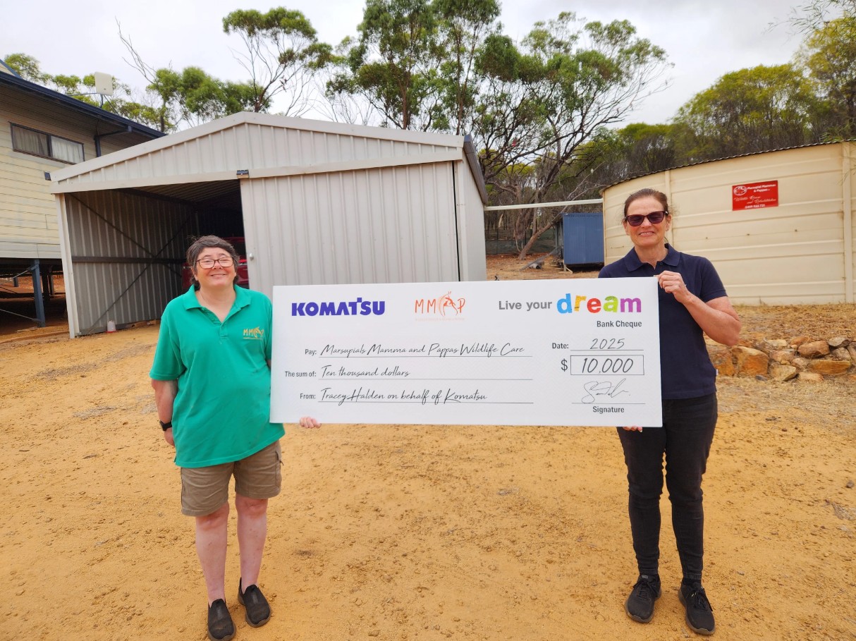 volunteers holding a large ceremonial cheque from Komatsu’s “live your dream” program