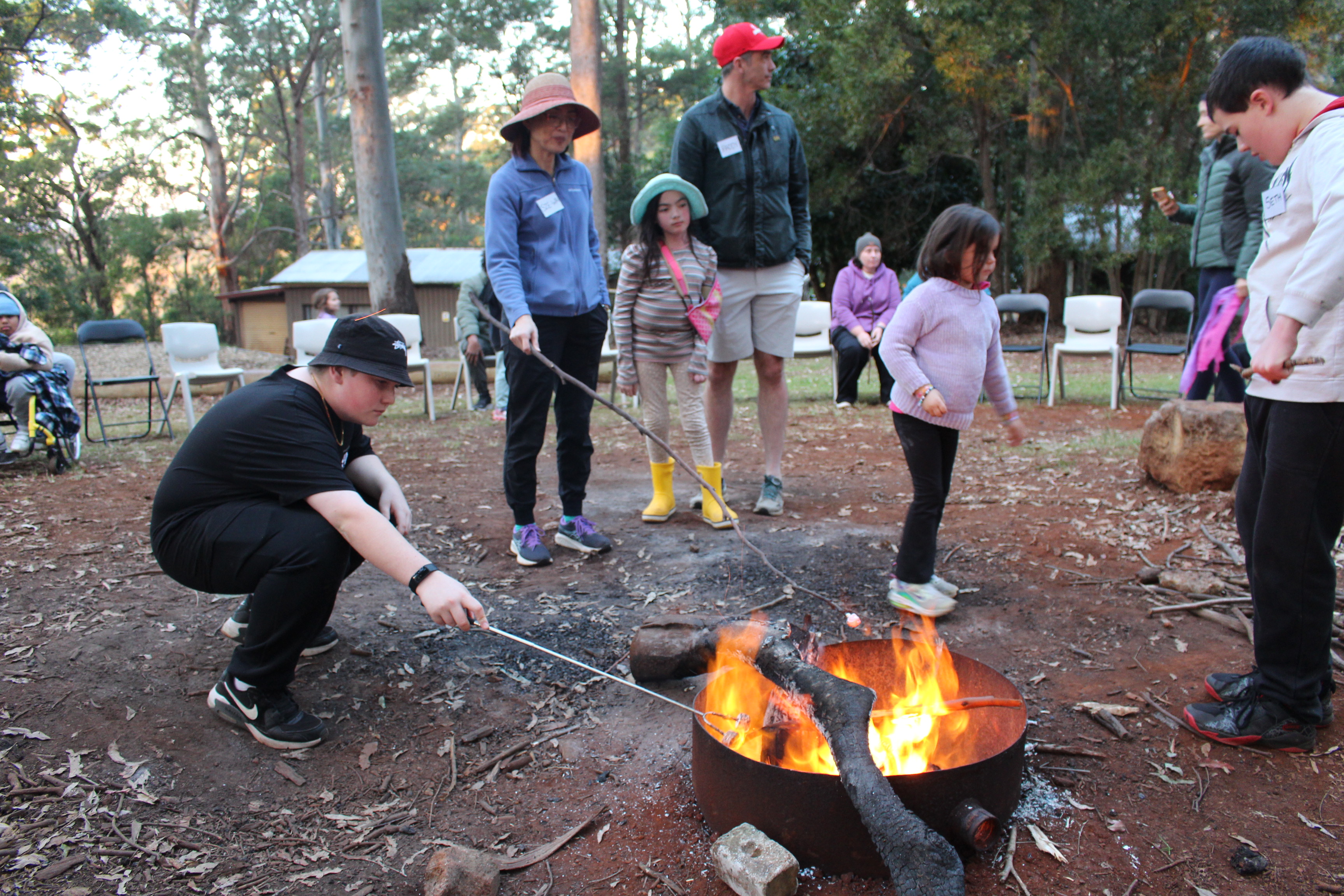 Family roasting marshmallows around campfire