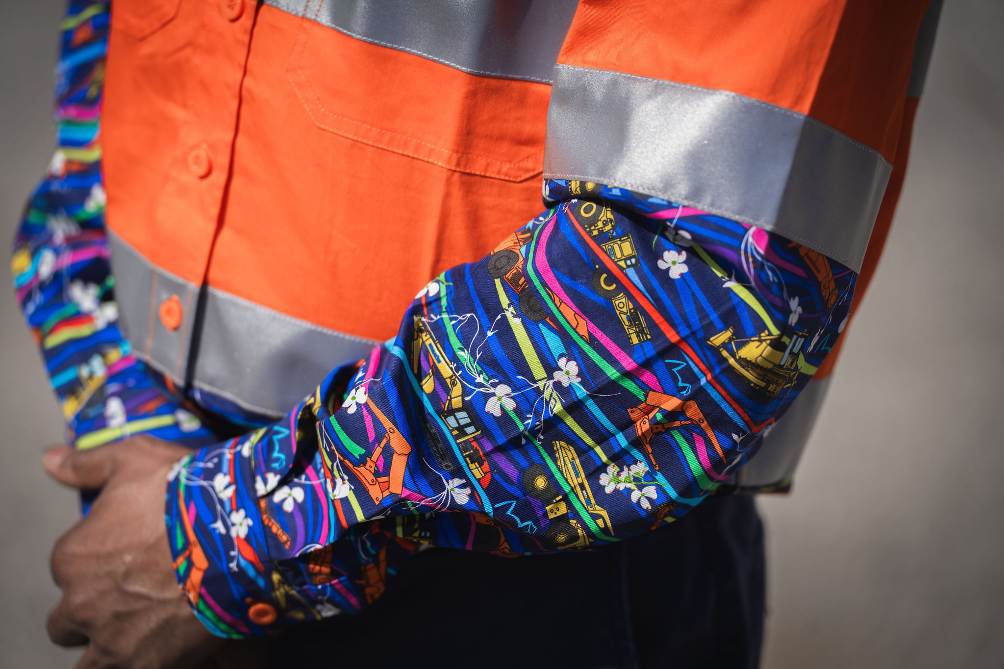 Close-up of a person wearing a vibrant patterned high visibility shirt.