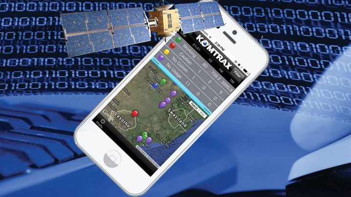 A hand holding a phone with the Komtrax mobile app on a worksite.