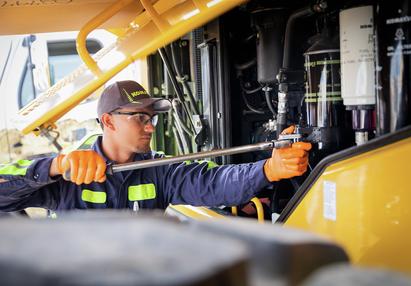 a komatsu technician repairing an piece of equipment