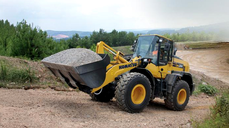 Komatsu mid-size wheel loader hauling gravel on a work site.