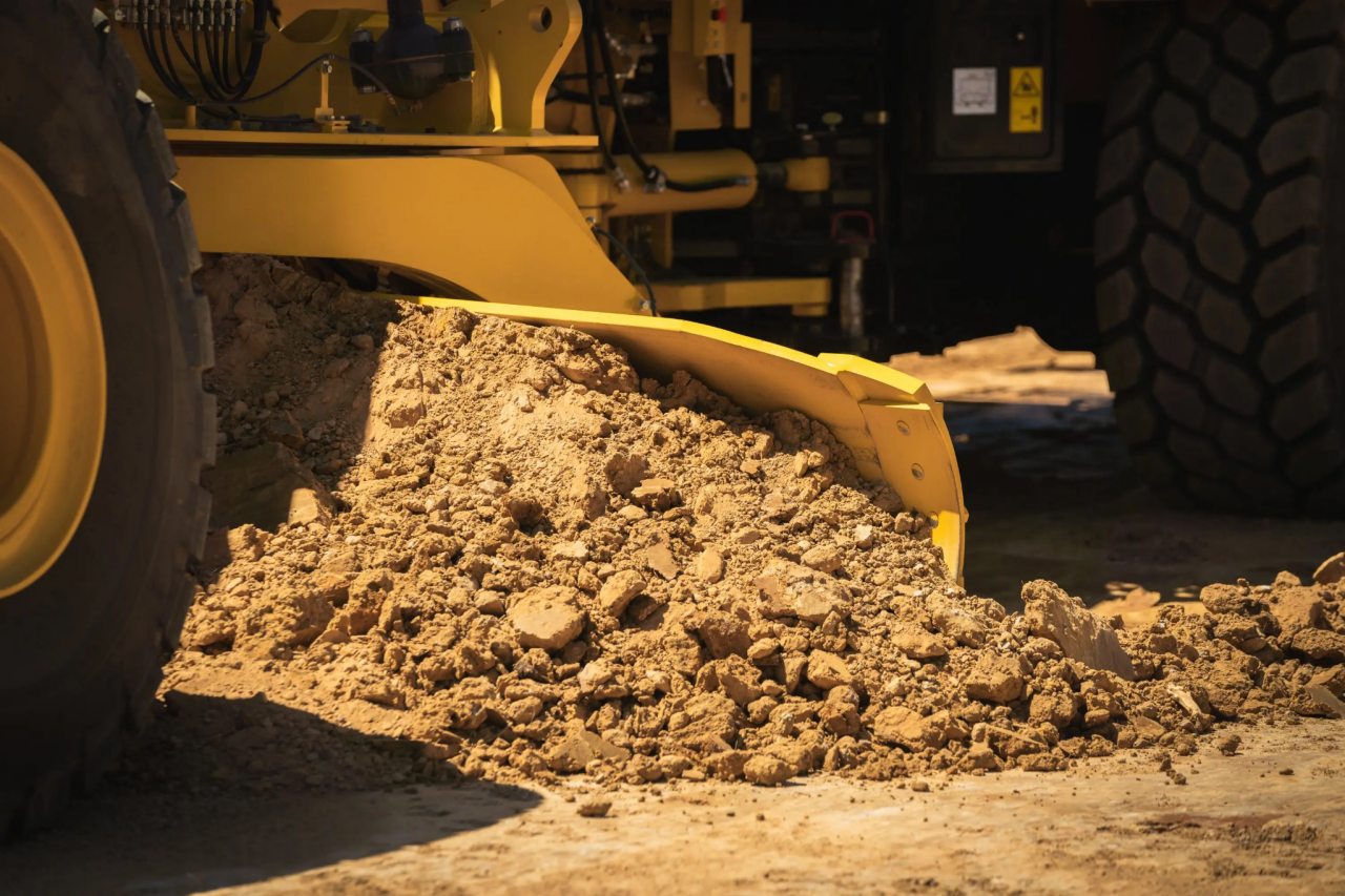 Close up of grading blade on machine pushing dirt